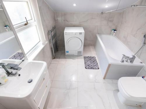 a white bathroom with a tub and a toilet and a sink at 2 bedroom house with free Parking, Aylesbury, Johns st in Buckinghamshire