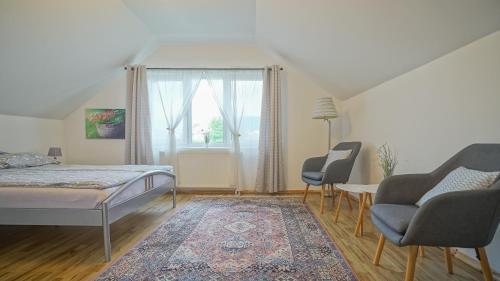 een slaapkamer met een bed en 2 stoelen en een raam bij Vilux with indoor private parking in Braşov