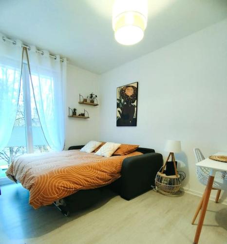 um quarto com uma cama e uma grande janela em Studio avec balcon à 5 min de la gare em Chalon-sur-Saône