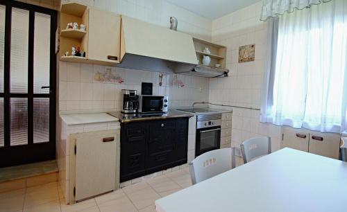 una cocina con electrodomésticos negros, mesa y sillas en Casa de piedra en Vilanova de Arousa, en Villanueva de Arosa