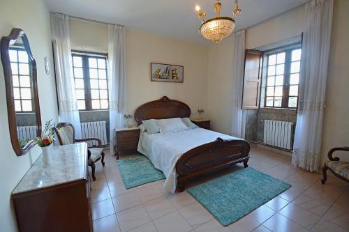 1 dormitorio con cama, mesa y ventanas en Casa de piedra en Vilanova de Arousa, en Villanueva de Arosa