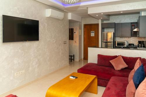 a living room with a red couch and a tv on a wall at PUERTO MARINA ASILAH in Asilah
