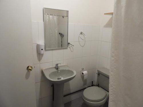 a white bathroom with a toilet and a sink at Hostal Ribera de Quitor in San Pedro de Atacama