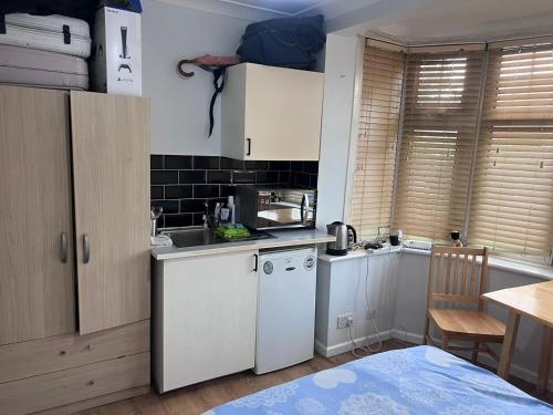 a kitchen with white cabinets and a sink and a table at HEART OF HANGER LANE in London