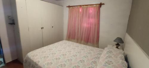 Habitación pequeña con cama y cortina rosa en El Remanso, en Durazno