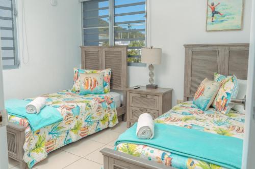 1 dormitorio con 2 camas y ventana en Modern Beach Walk at Puerto Bahia #30, en Rincón