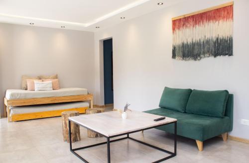 ein Wohnzimmer mit einem Sofa, einem Tisch und einem Bett in der Unterkunft Apart Hotel Jardín in El Calafate