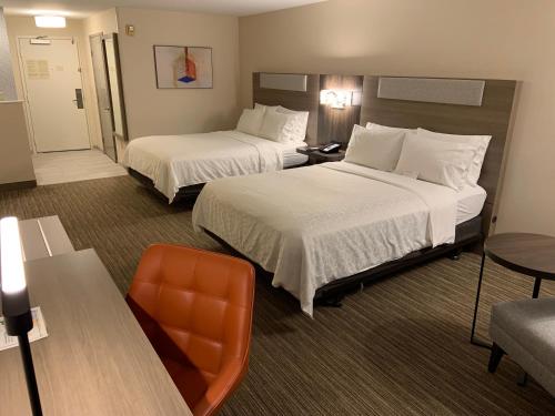 a hotel room with two beds and a chair at Holiday Inn Express Hotel & Suites Hermosa Beach by IHG in Hermosa Beach