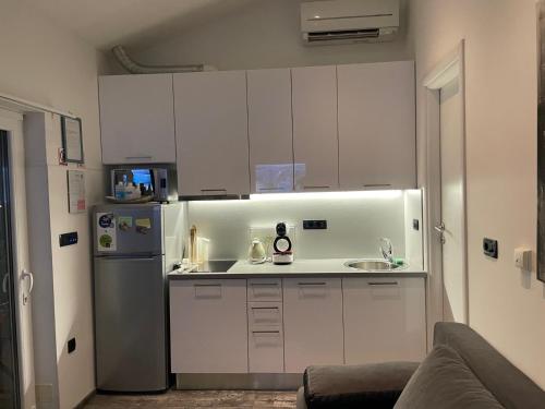 eine kleine Küche mit weißen Schränken und einem Kühlschrank in der Unterkunft Shanti Home in Lovran