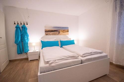 クックスハーフェンにあるStrandrobbe-2の白いベッド(青い枕付)が備わるベッドルームです。