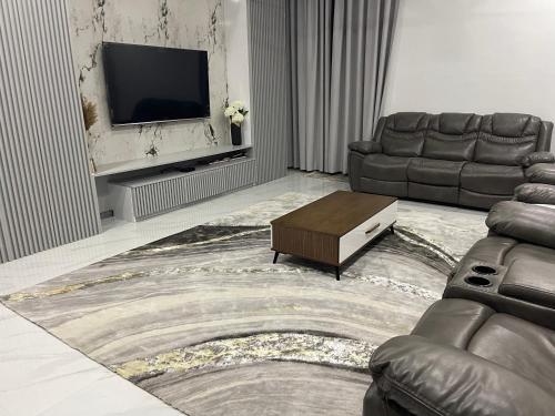a living room with a couch and a tv at Kibada White Villa in Dar es Salaam