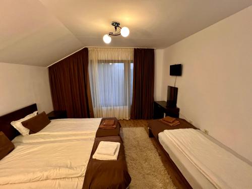 een hotelkamer met 2 bedden en een raam bij Къщи за гости Фантазия in Dospat