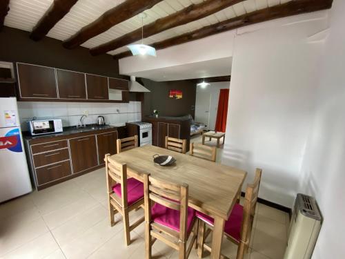 una cocina con mesa de madera y sillas. en Raices Departamento 2, en San Rafael