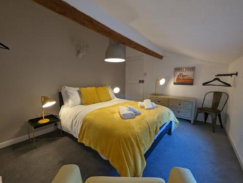 a bedroom with a bed with yellow sheets and chairs at Rush Hill Cottage - with parking for 2 cars in Bath