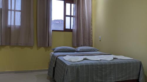 a bedroom with a bed with blue pillows and a window at Casa Calumbé do Vale, na vila do Vale do Capão in Vale do Capao