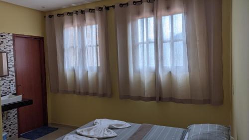 a bedroom with a bed and two windows at Casa Calumbé do Vale, na vila do Vale do Capão in Vale do Capao