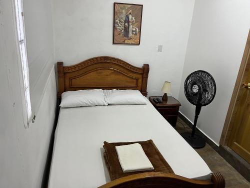 a bedroom with a white bed with a wooden headboard and a fan at Casa Grande in Medellín