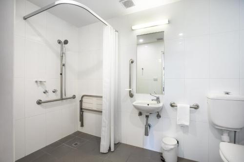 Baño blanco con aseo y lavamanos en Doncaster Apartments by Nightcap Plus, en Doncaster