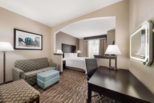 a hotel room with a couch and a bed at SureStay Plus Hotel by Best Western Plano in Plano