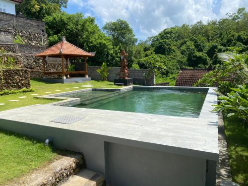 a swimming pool in a garden with a gazebo at Belong Bunter Homestay in Uluwatu