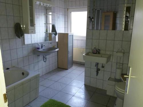 uma casa de banho com 2 lavatórios, uma banheira e um WC. em worker-flat em Gelsenkirchen