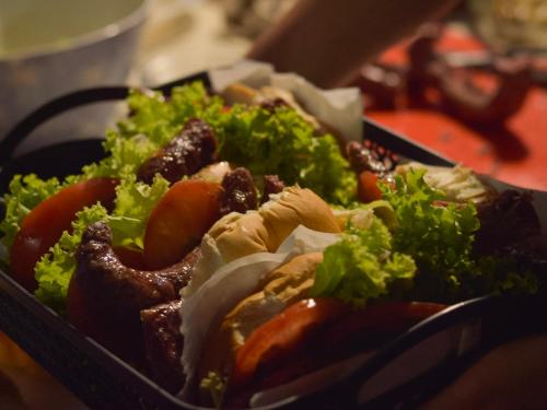 a tray of food with a salad and sausage at Mar de Fondo Hostel in Punta Del Diablo