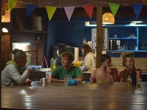 a group of people sitting at a table in a restaurant at Mar de Fondo Hostel in Punta Del Diablo