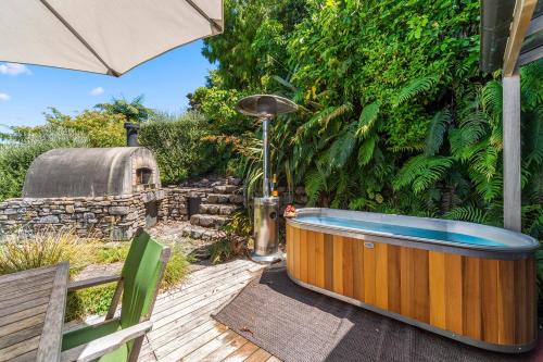 a hot tub sitting on a wooden deck with an umbrella at Wai Marino - Taupo in Taupo