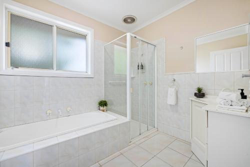 a white bathroom with a tub and a shower at Skip, Shop, Splash in Rye