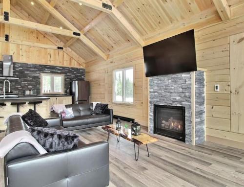 a living room with a couch and a fireplace at Chalet l'amical avec Spa in Saint-Philémon