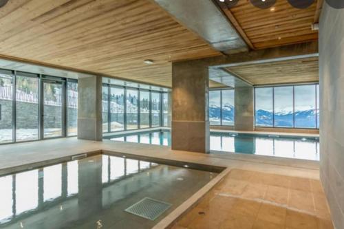 - une piscine dans un bâtiment avec fenêtres dans l'établissement Arc 1600 SunsetPanorama Skis aux pieds 6 pers, à Bourg-Saint-Maurice