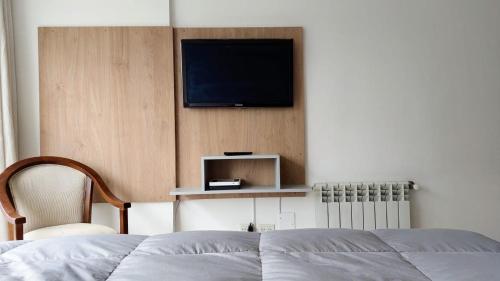 1 dormitorio con 1 cama y TV en la pared en Bariloche Studio en San Carlos de Bariloche