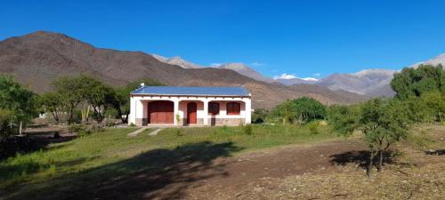 uma pequena casa num campo com montanhas ao fundo em Casa de CAMPO HUAKA HUASY em Cachí