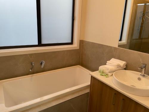a bathroom with a sink and a bath tub and a sink at Entire 4 Bedroom Brand New Home In Melton South ! in Melton South
