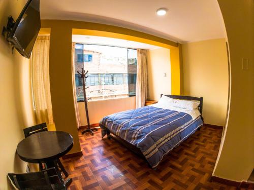 a bedroom with a bed and a table and a window at Hotel Sol de Oro Ayacucho in Ayacucho