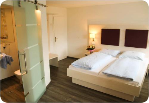 a bedroom with a large white bed and a bathroom at Hotel Bedburger Mühle in Bedburg