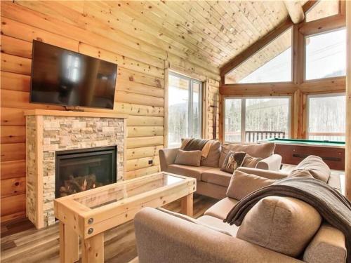a living room with a fireplace and a tv at Le Billot- Chalet Rustic avec Spa in Saint-Philémon