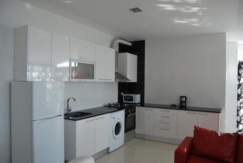 cocina con armarios blancos, lavadora y secadora en Apartamentos 7 saias, en Nazaré