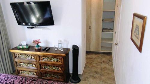 a television hanging on a wall next to a dresser at BELLAS VILLAS, VILLA AMOR HERMOSA CASA a UN ACCECIBLE PRECIO in San Miguel de Allende