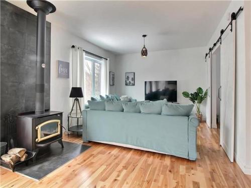 a living room with a blue couch and a fireplace at LE FÉÉRIQUE- CHALET AVEC SPA in Saint-Philémon