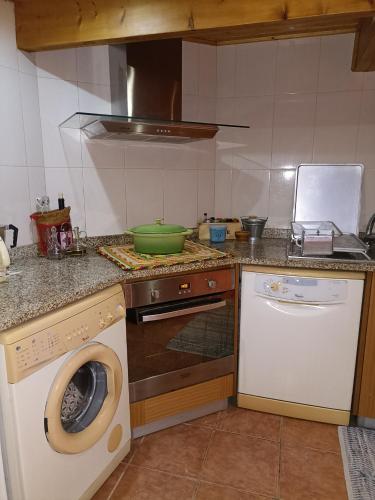 a kitchen with a washing machine and a dishwasher at Casa do Soito. in Avelãs de Ambom