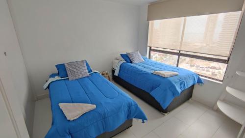 two beds in a small room with a window at DEPTO SUITE II in Iquique