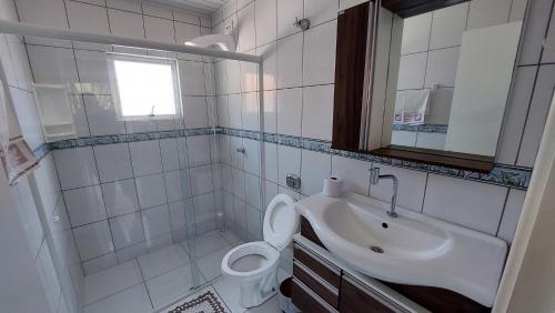 a bathroom with a sink and a toilet and a mirror at Casa Beira Mar Mariscal Superior in Bombinhas