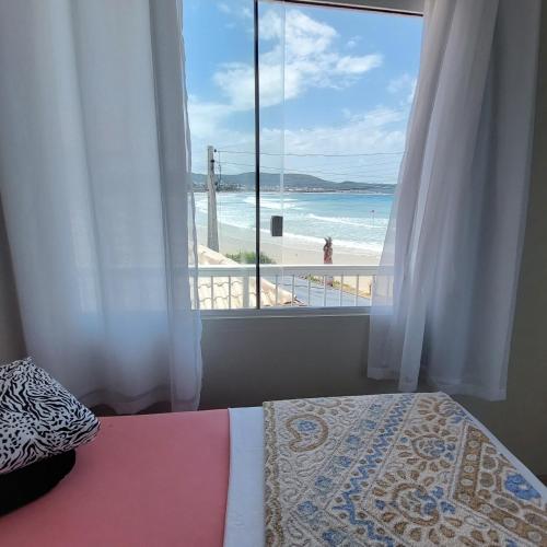 a bedroom with a bed and a view of the beach at Casa Beira Mar Mariscal Superior in Bombinhas