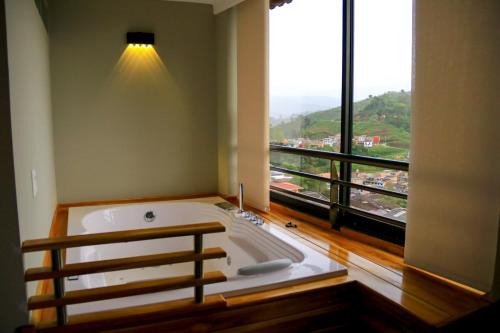 eine große Badewanne in einem Zimmer mit einem großen Fenster in der Unterkunft Hotel Entre Brumas in Aguadas