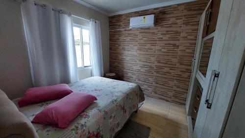 Un dormitorio con una cama con almohadas rosas. en Casa Beira Mar Mariscal Terreo, en Bombinhas