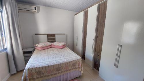 a bedroom with a bed with two pink pillows on it at Casa Beira Mar Mariscal 1 in Bombinhas