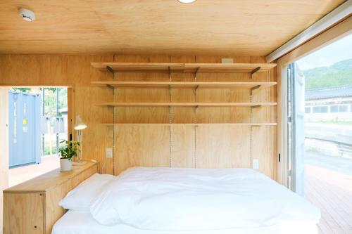 Bett in einem Zimmer mit einer Holzwand in der Unterkunft 安全第一 客室　コンテナハウス in Nishiawakura