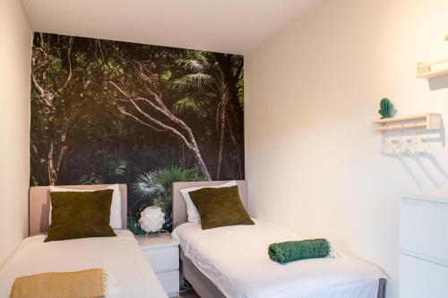 two beds in a room with a painting on the wall at Blue Bay Resort luxury apartment Green View in Sint Michiel