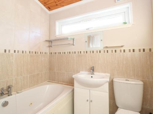 y baño con lavabo, bañera y aseo. en Brightwater Lodge en Windermere
